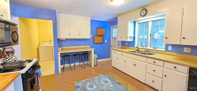 kitchen featuring washer / clothes dryer, black appliances, and white cabinetry