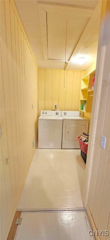 laundry area featuring washer and dryer and wood walls