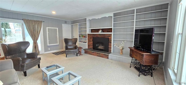 carpeted living room with a brick fireplace and wooden walls