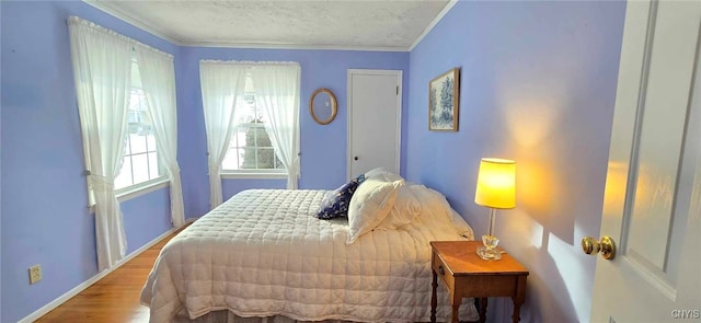 bedroom featuring wood-type flooring, a textured ceiling, and crown molding