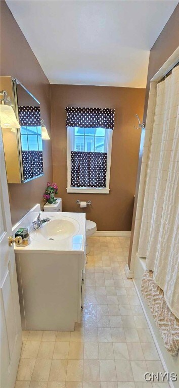 full bathroom featuring toilet, vanity, and shower / tub combo with curtain