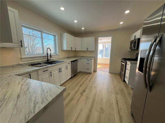 kitchen with appliances with stainless steel finishes, sink, white cabinets, and light stone counters