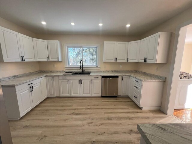 kitchen featuring white cabinetry, stainless steel dishwasher, light hardwood / wood-style floors, and sink