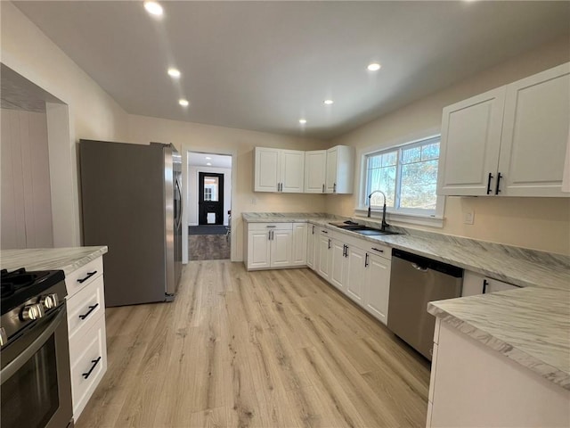 kitchen featuring white cabinetry, appliances with stainless steel finishes, sink, and light wood-type flooring