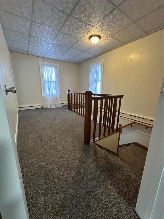 8074 State Route 90, Montezuma, NY 13040 - corridor featuring a baseboard heating unit, an upstairs landing, baseboards, and a paneled ceiling