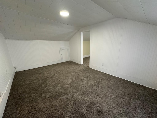 bonus room with vaulted ceiling and dark colored carpet