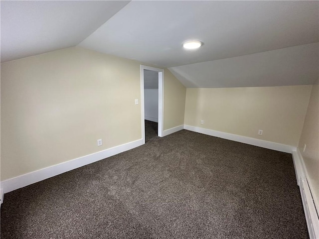 additional living space featuring dark carpet and vaulted ceiling