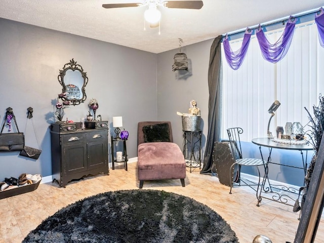 living area with ceiling fan and a textured ceiling