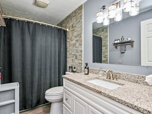 bathroom with wood-type flooring, a textured ceiling, toilet, and vanity