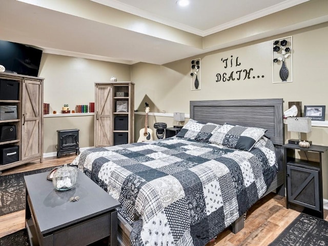 bedroom featuring wood-type flooring, a barn door, and ornamental molding