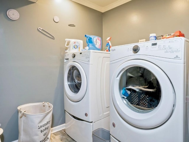 clothes washing area with washer and clothes dryer and ornamental molding