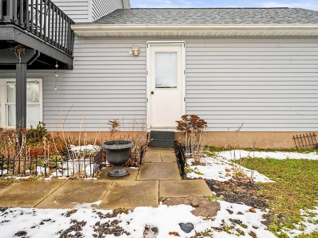 snow covered property entrance featuring a balcony