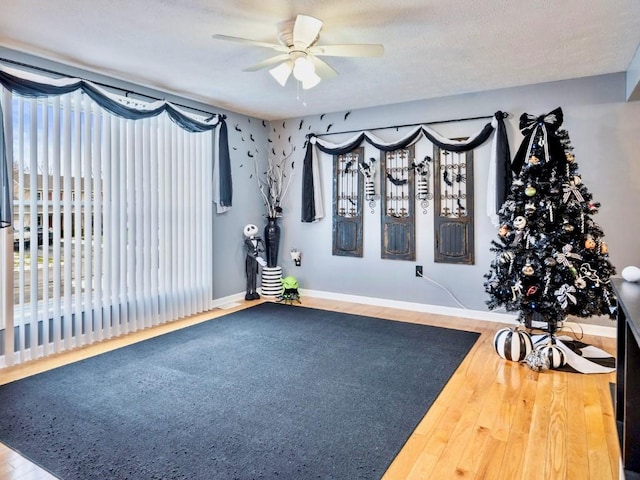 workout room with ceiling fan, hardwood / wood-style floors, and a textured ceiling