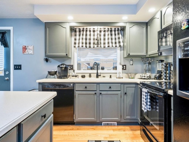 kitchen with sink, black appliances, and light hardwood / wood-style floors