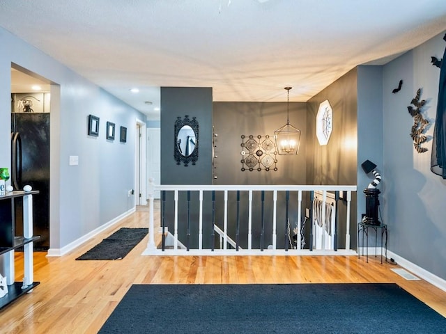 corridor featuring a chandelier and wood-type flooring