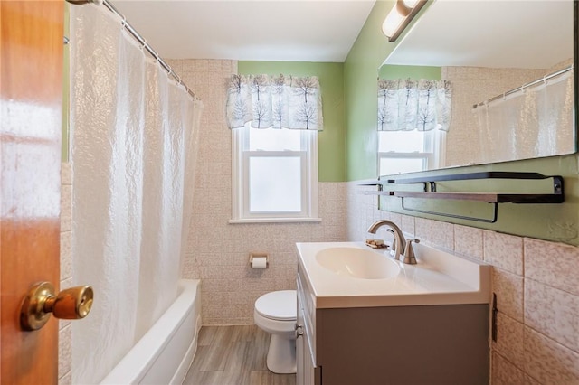 full bathroom with toilet, hardwood / wood-style flooring, tile walls, shower / bath combination with curtain, and vanity