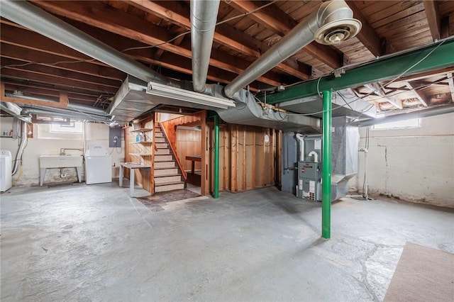 basement with sink, a healthy amount of sunlight, heating unit, and washer / dryer