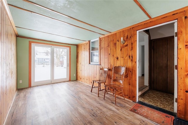 living area with wooden walls, crown molding, and wood-type flooring