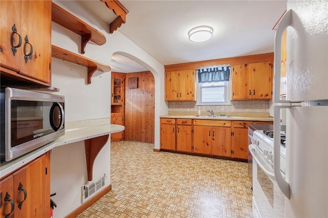 kitchen featuring sink, white appliances, and tasteful backsplash