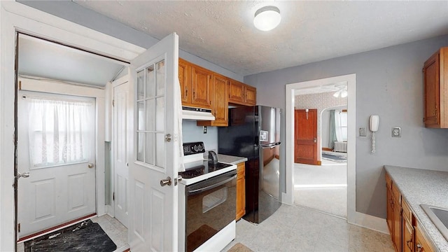 kitchen featuring brown cabinetry, under cabinet range hood, freestanding refrigerator, electric stove, and arched walkways