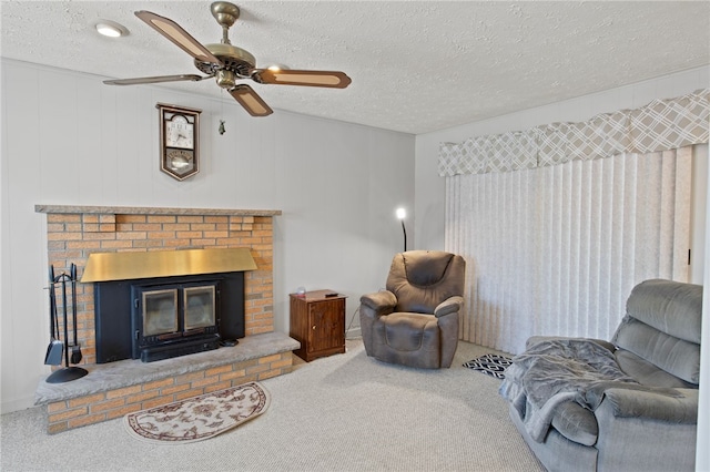 living room with ceiling fan, a textured ceiling, carpet flooring, and a fireplace