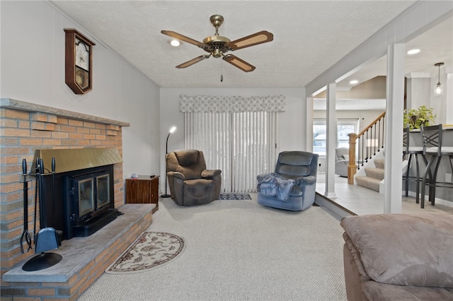 carpeted living room featuring ceiling fan, a textured ceiling, and a fireplace