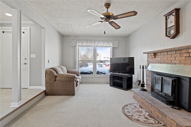 carpeted living room with ceiling fan, a brick fireplace, crown molding, and a textured ceiling