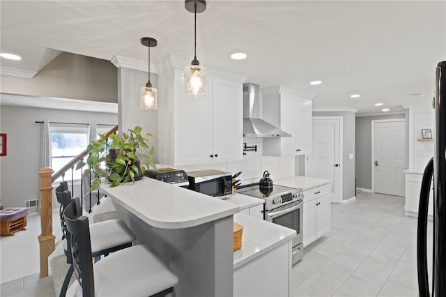 kitchen featuring appliances with stainless steel finishes, white cabinetry, hanging light fixtures, a breakfast bar, and wall chimney exhaust hood