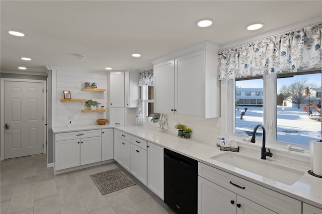 kitchen with sink, white cabinets, light stone counters, and black dishwasher