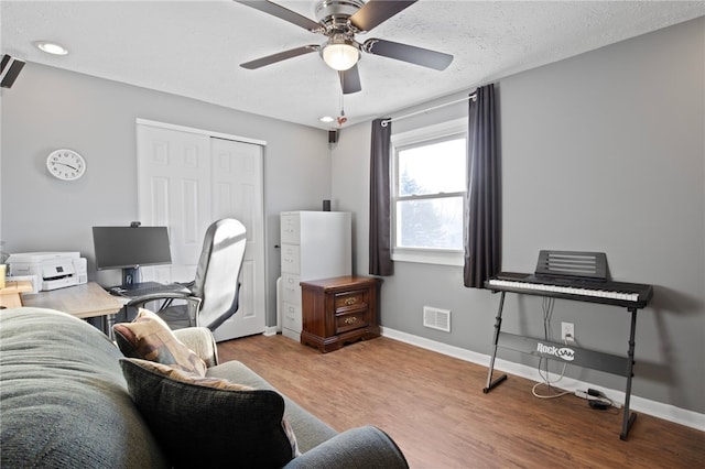 office space featuring ceiling fan, light hardwood / wood-style floors, and a textured ceiling