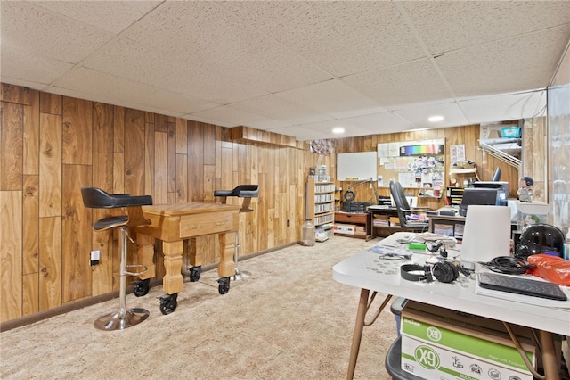 office space with light colored carpet, a paneled ceiling, and wooden walls