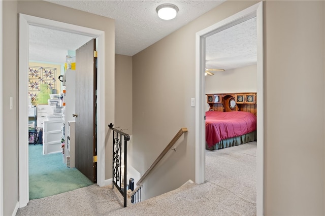 corridor with light colored carpet and a textured ceiling