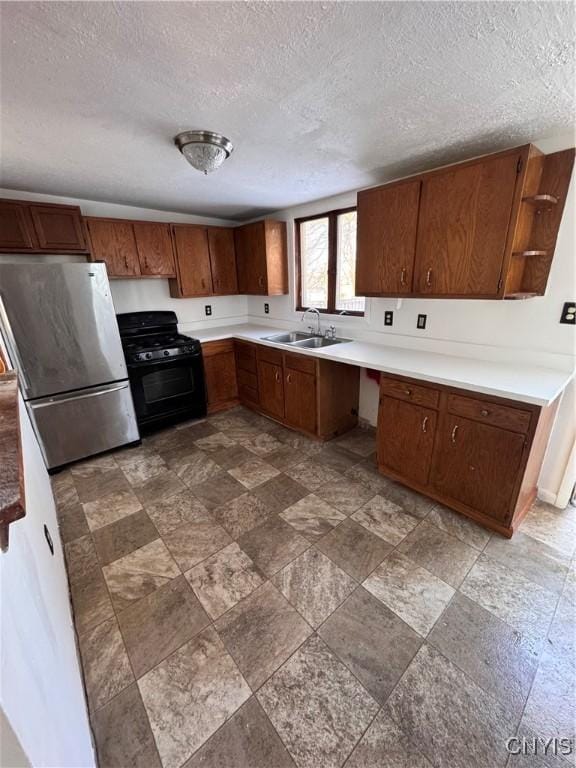 kitchen with sink, a textured ceiling, stainless steel fridge, and gas stove