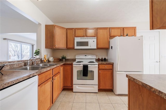 kitchen featuring sink, white appliances, light tile patterned floors, and a textured ceiling