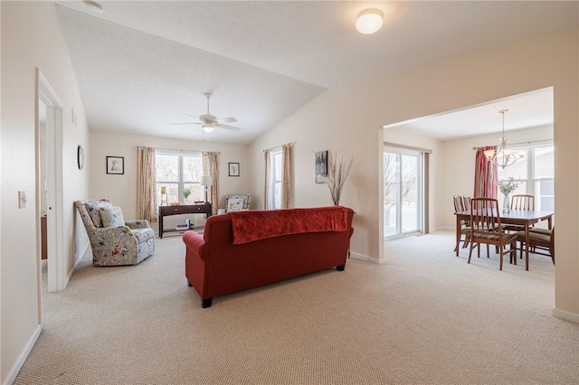 carpeted living room featuring vaulted ceiling and ceiling fan with notable chandelier