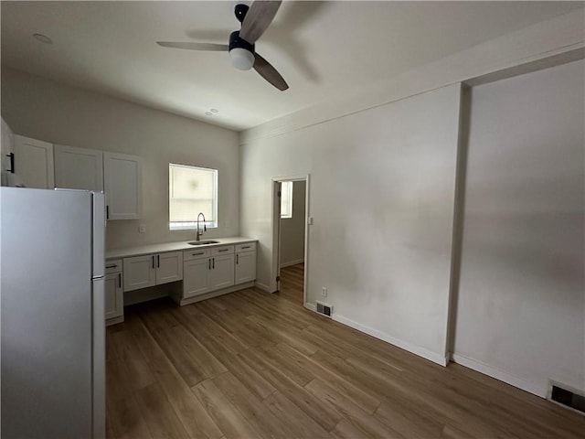 kitchen featuring ceiling fan, sink, light wood-type flooring, white cabinetry, and white fridge