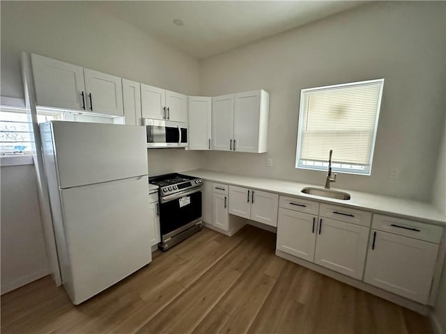 kitchen featuring white fridge, white cabinets, sink, a healthy amount of sunlight, and electric stove