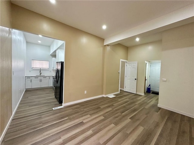 spare room with sink, a towering ceiling, and wood-type flooring