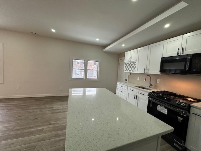 kitchen featuring sink, black appliances, white cabinetry, and light stone countertops