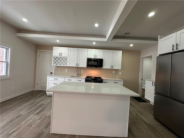 kitchen featuring white cabinets, a kitchen island, stainless steel refrigerator, light stone counters, and stove