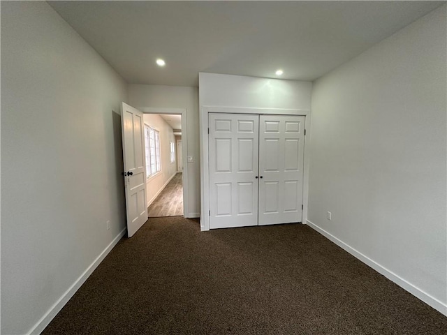 unfurnished bedroom featuring a closet and dark carpet