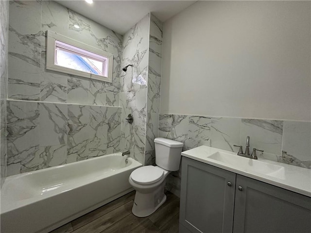 full bathroom featuring tile walls, hardwood / wood-style flooring, tiled shower / bath, toilet, and vanity