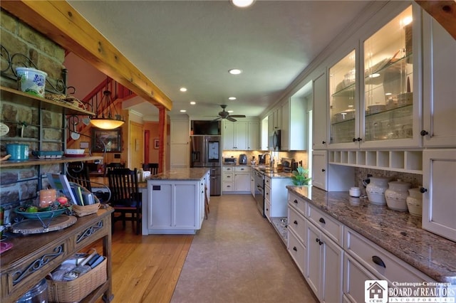 kitchen featuring light stone counters, white cabinetry, a center island, and stainless steel appliances