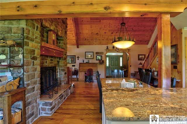 kitchen featuring light stone countertops, wood ceiling, a fireplace, hanging light fixtures, and hardwood / wood-style flooring