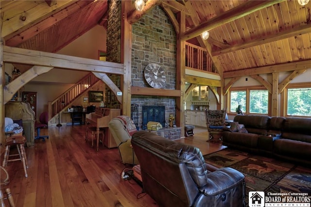 living room with hardwood / wood-style flooring, beamed ceiling, a stone fireplace, and high vaulted ceiling