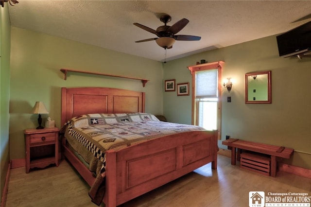 bedroom with ceiling fan, light hardwood / wood-style flooring, and a textured ceiling