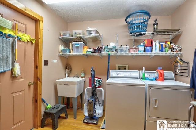 clothes washing area featuring hardwood / wood-style flooring, a textured ceiling, and washer and dryer