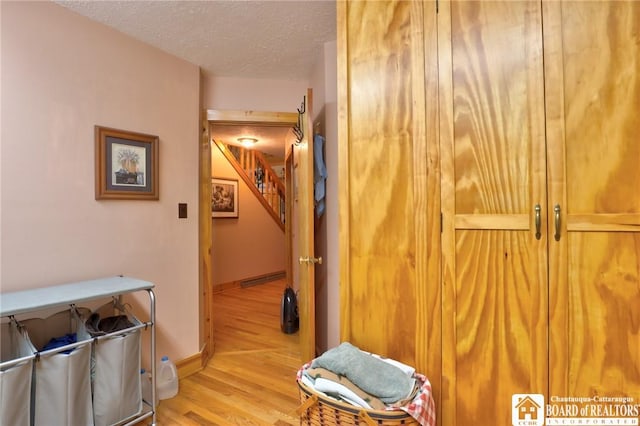 hallway featuring light hardwood / wood-style floors and a textured ceiling