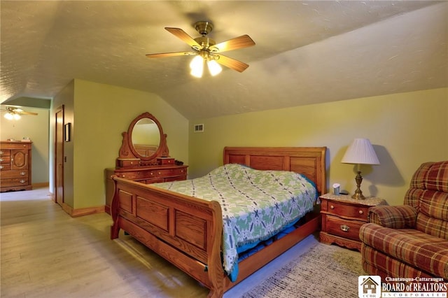 bedroom with light hardwood / wood-style flooring, vaulted ceiling, and ceiling fan