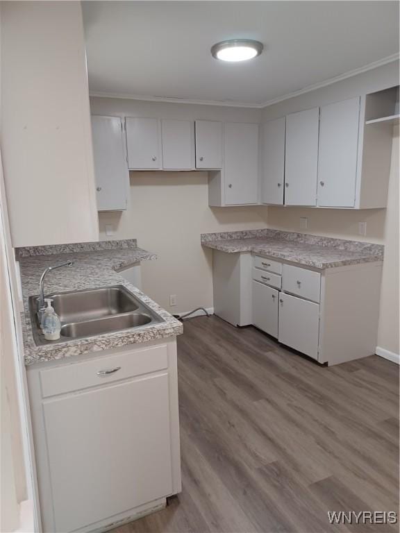 kitchen with sink, white cabinetry, ornamental molding, and light wood-type flooring